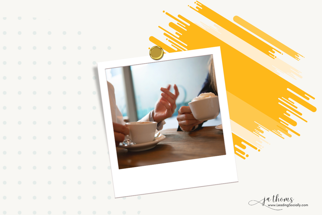 two women sitting at a table with coffee in hand having a conversation